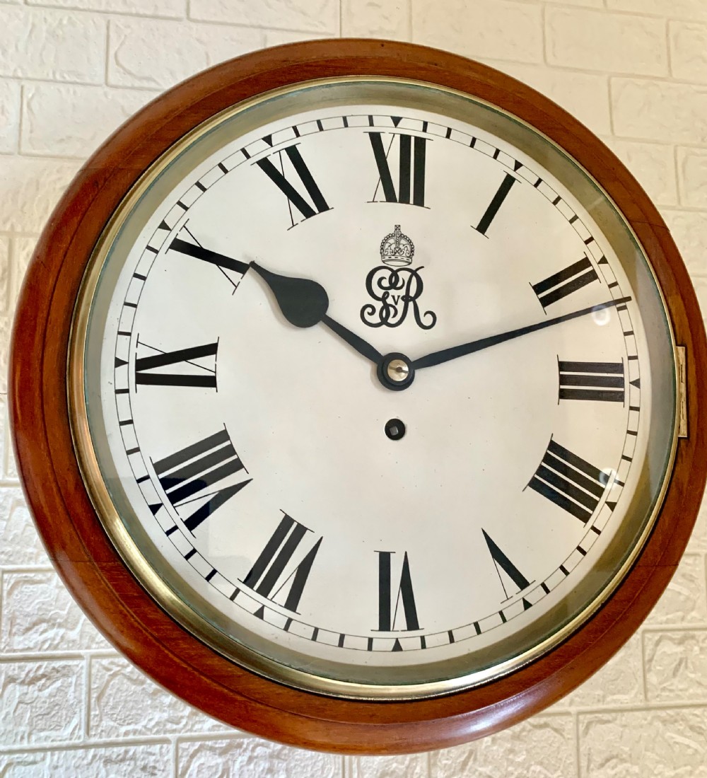A circular antique fusee wall clock featuring a warm mahogany wooden surround, a brass glass bezel, and a white painted dial with black Roman numerals and a GVR royal cypher monogram. View IV