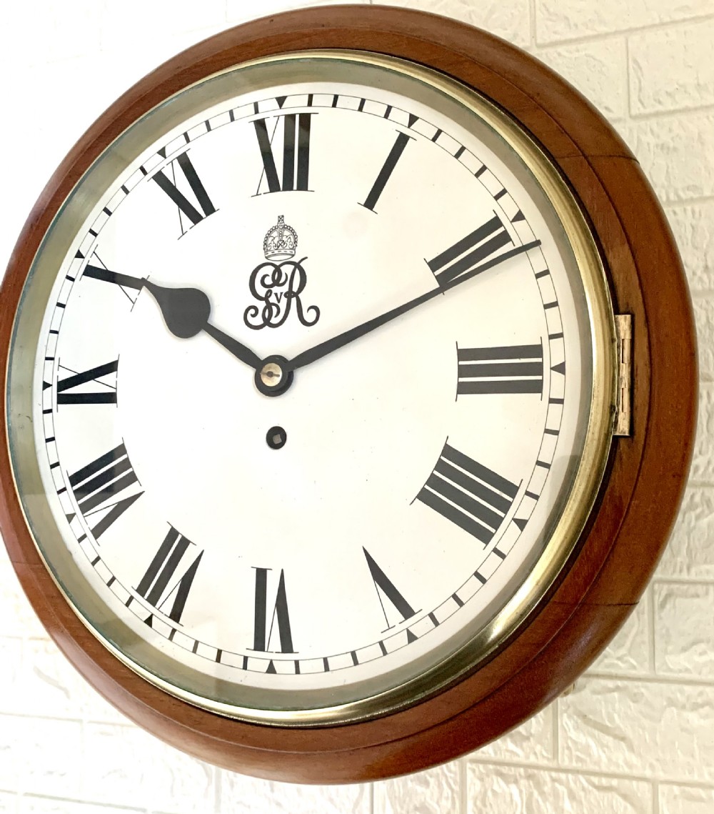 A circular antique fusee wall clock featuring a warm mahogany wooden surround, a brass glass bezel, and a white painted dial with black Roman numerals and a GVR royal cypher monogram. View V