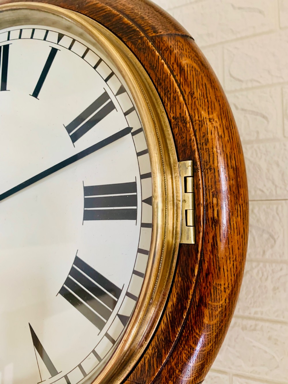 A circular wooden wall clock with a white dial, Roman numerals, black hands, and official G.P.O. markings set within a brass bezel. View III