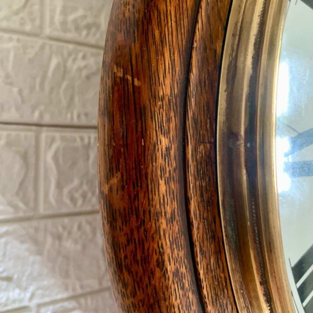 A circular wooden wall clock with a white dial, Roman numerals, black hands, and official G.P.O. markings set within a brass bezel. View IX