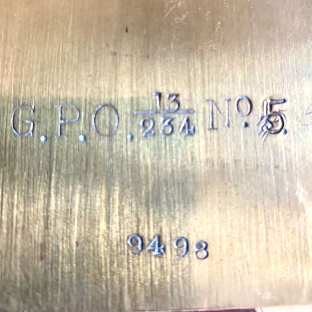 A circular wooden wall clock with a white dial, Roman numerals, black hands, and official G.P.O. markings set within a brass bezel. View XIII