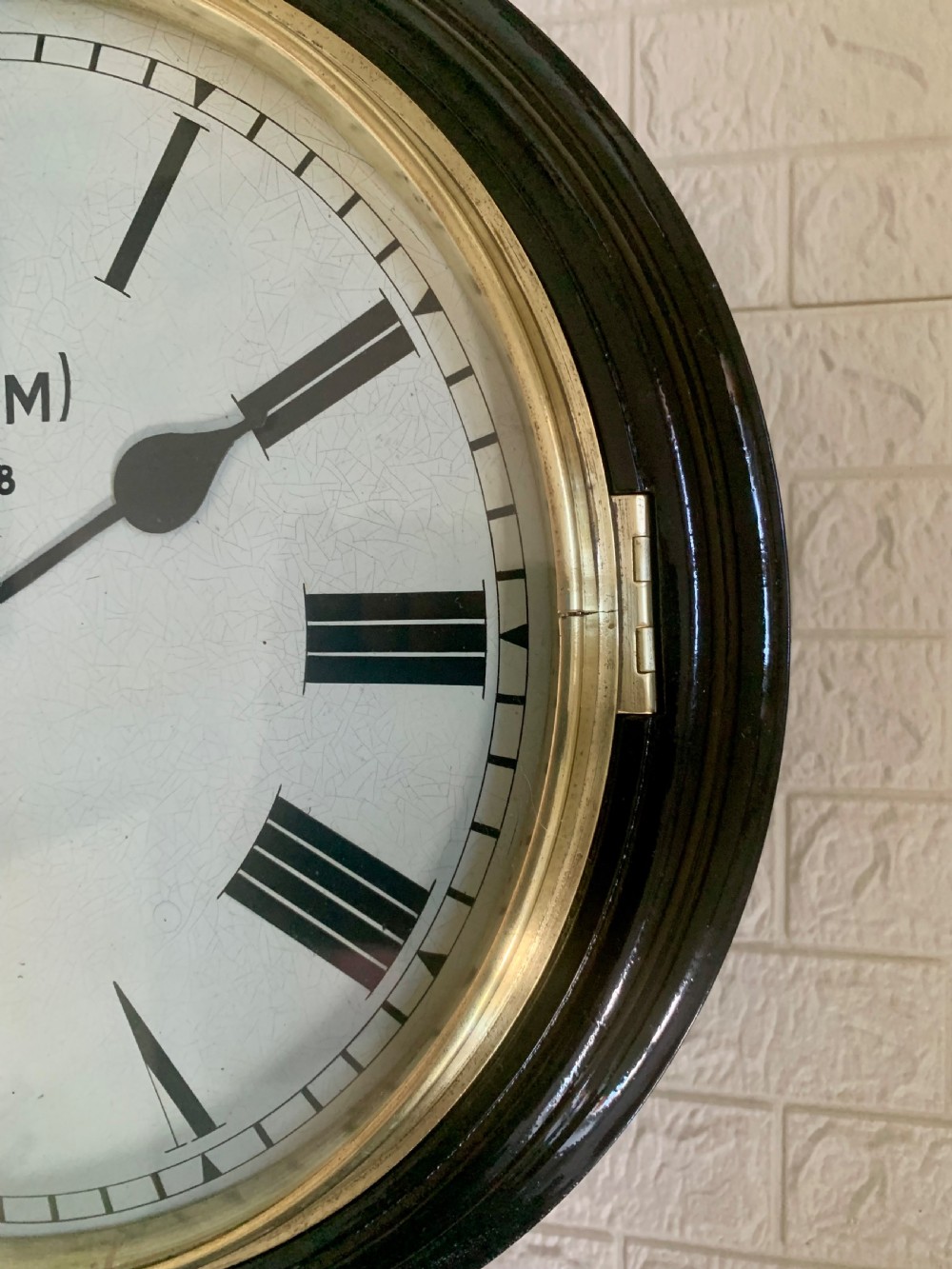 A circular wall clock with a dark painted wooden frame, a brass bezel, and a white dial displaying black Roman numerals and British Railways lettering. View V