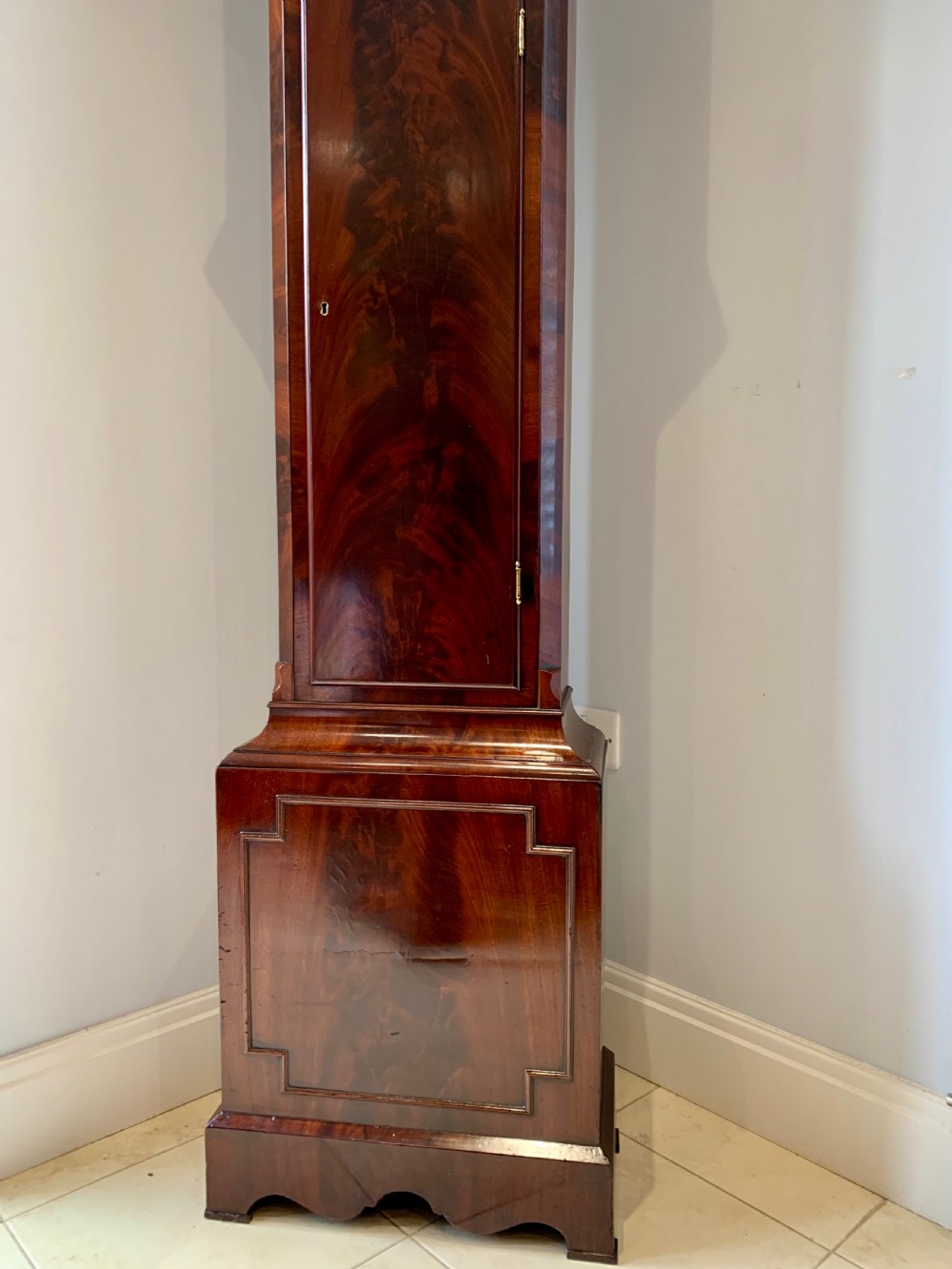 A Regency flame mahogany longcase clock featuring a circular dial signed Bennet London, topped with a pediment and three brass ball finials. View IX