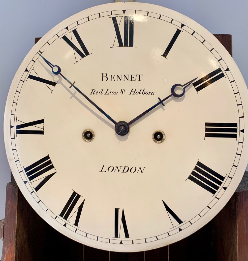 A Regency flame mahogany longcase clock featuring a circular dial signed Bennet London, topped with a pediment and three brass ball finials. View XVIII