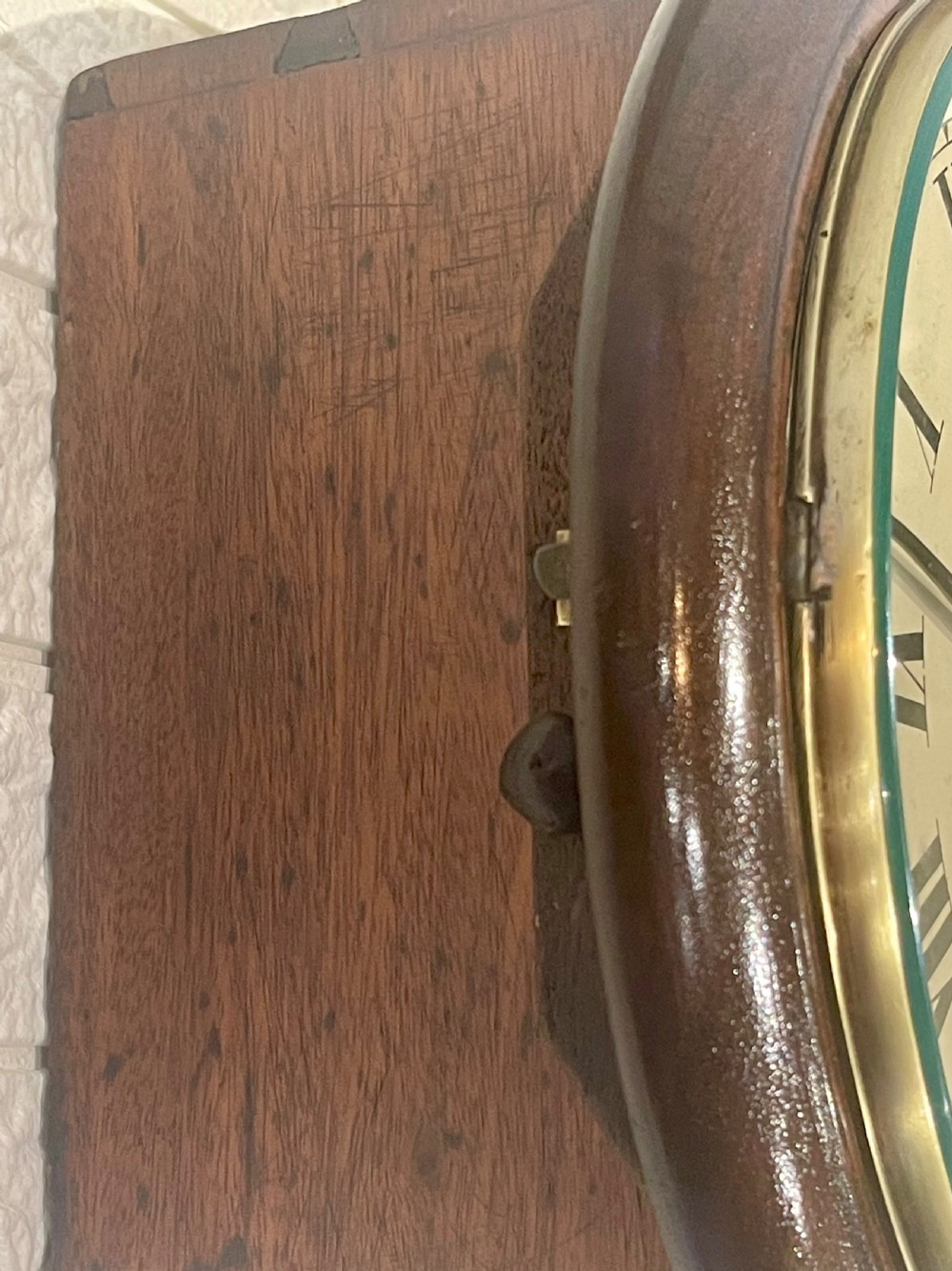 An antique circular mahogany wall clock with a brass-hinged glass bezel, white dial featuring Roman numerals, and black markings reading LMSR John Walker London. View IX