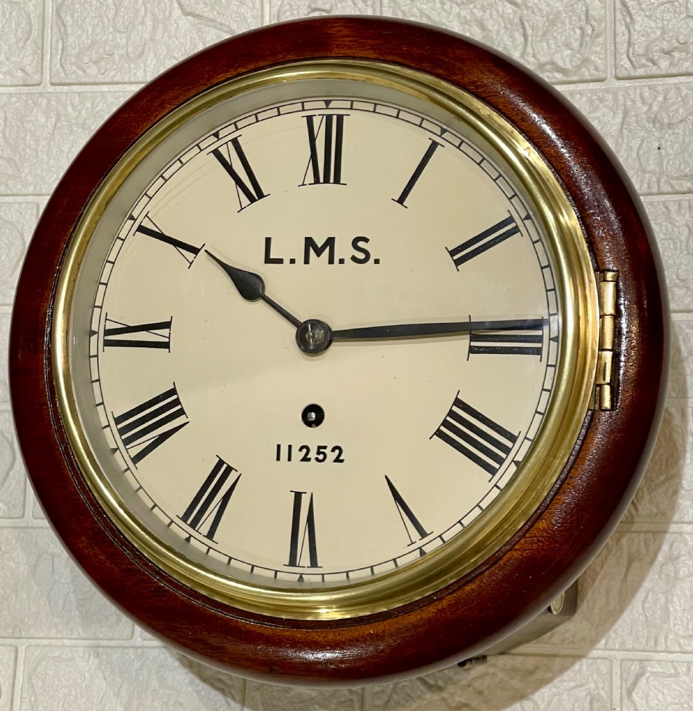 A circular mahogany wall clock with a brass bezel, off-white dial displaying Roman numerals, and London Midland and Scottish Railway branding. View II