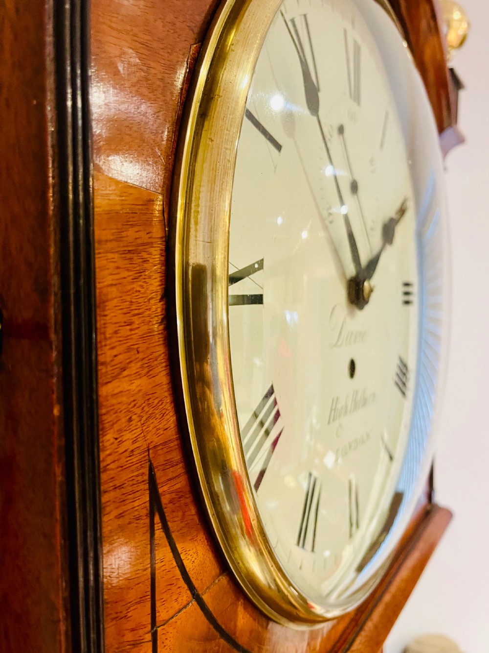 A Georgian flame mahogany longcase clock featuring three brass urn finials, a circular dial signed Davie High Holborn London, and a long arched trunk door. View XV