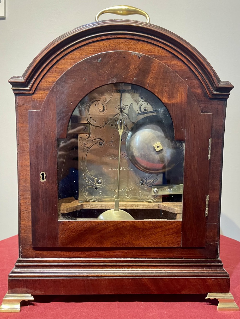 A George III mahogany bracket clock featuring an arched top with a brass handle, a circular white dial with Roman numerals, and brass bracket feet. View VIII