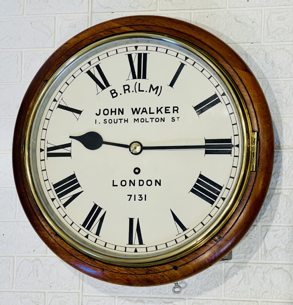 A circular mahogany framed fusee wall clock featuring a cream painted dial with Roman numerals, a brass hinged bezel, and British Rail London Midland markings. View III