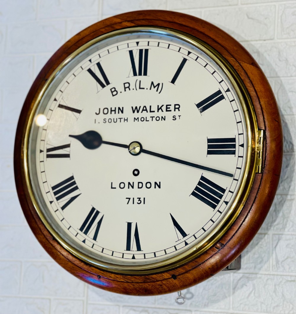 A circular mahogany framed fusee wall clock featuring a cream painted dial with Roman numerals, a brass hinged bezel, and British Rail London Midland markings. View IV