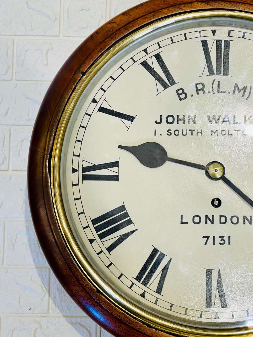 A circular mahogany framed fusee wall clock featuring a cream painted dial with Roman numerals, a brass hinged bezel, and British Rail London Midland markings. View XI