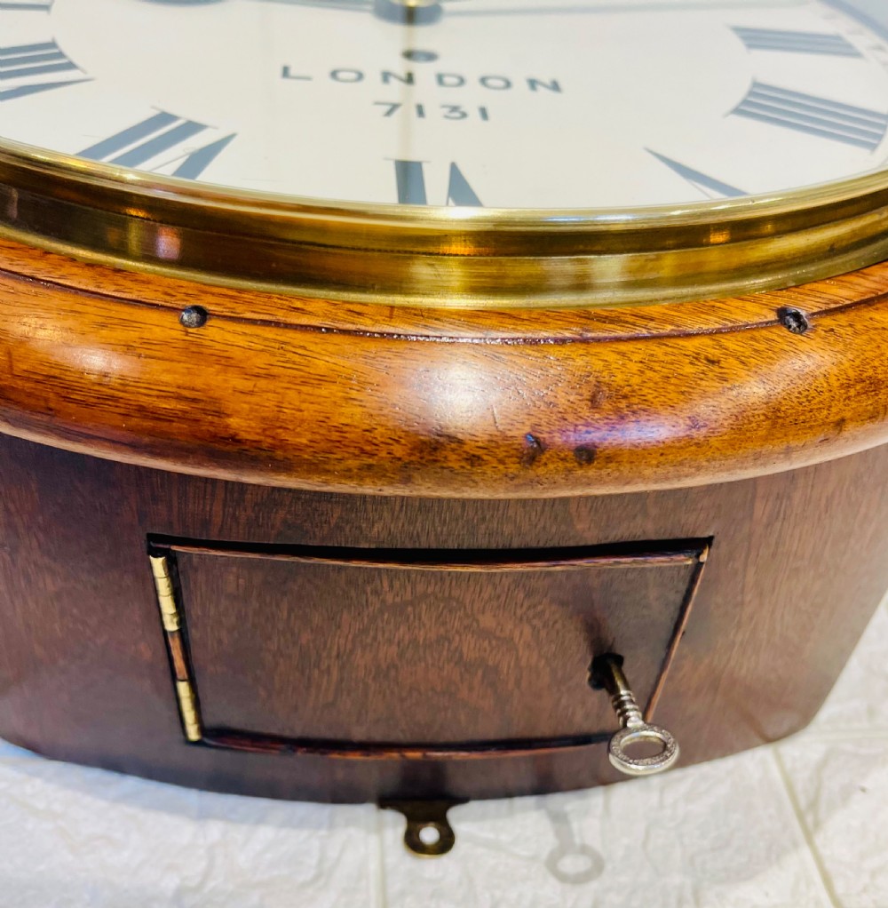 A circular mahogany framed fusee wall clock featuring a cream painted dial with Roman numerals, a brass hinged bezel, and British Rail London Midland markings. View XIII