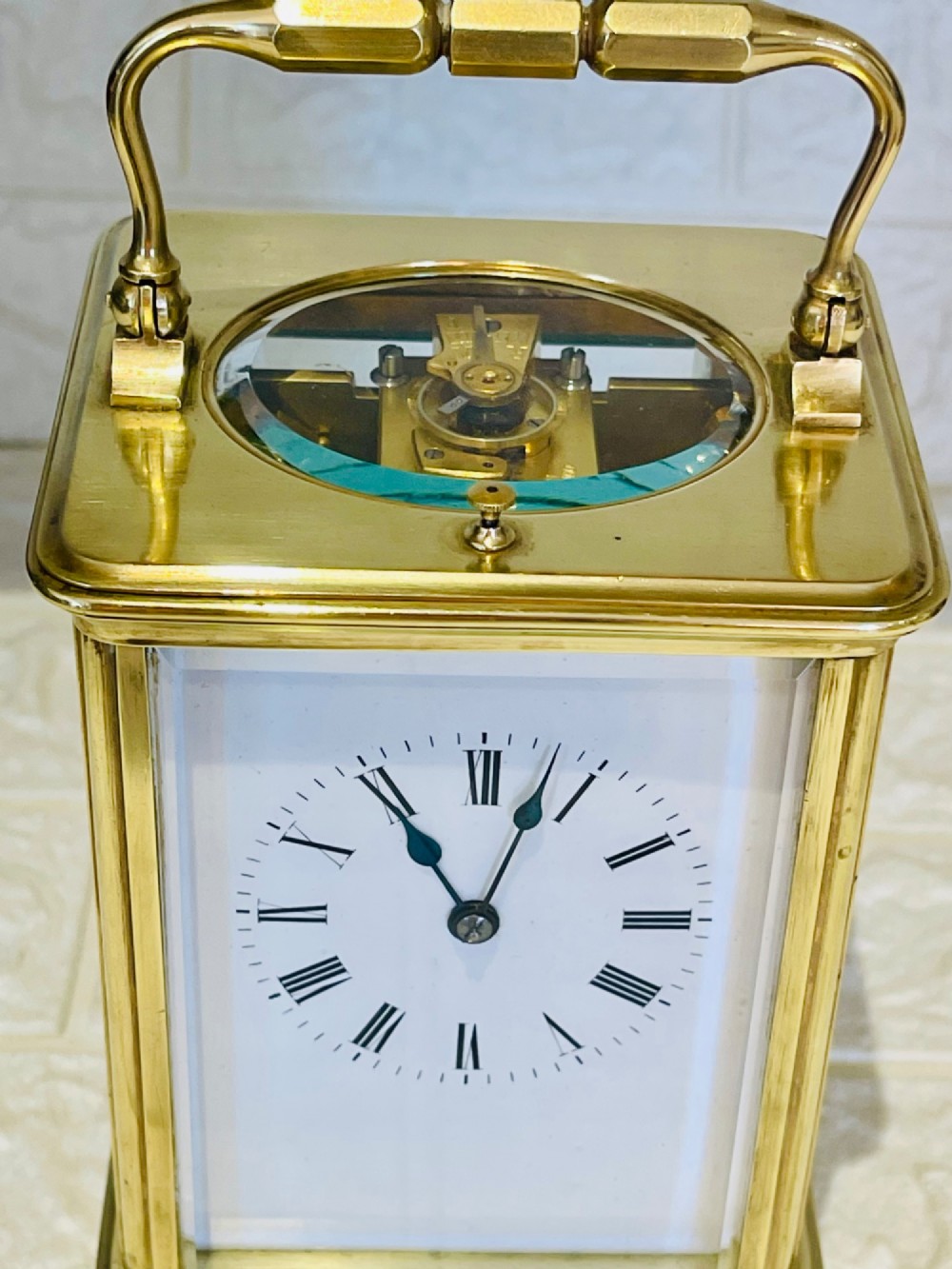 An antique brass carriage clock featuring a rectangular glass case, top carrying handle, and a white enamel dial with black Roman numerals. View VIII