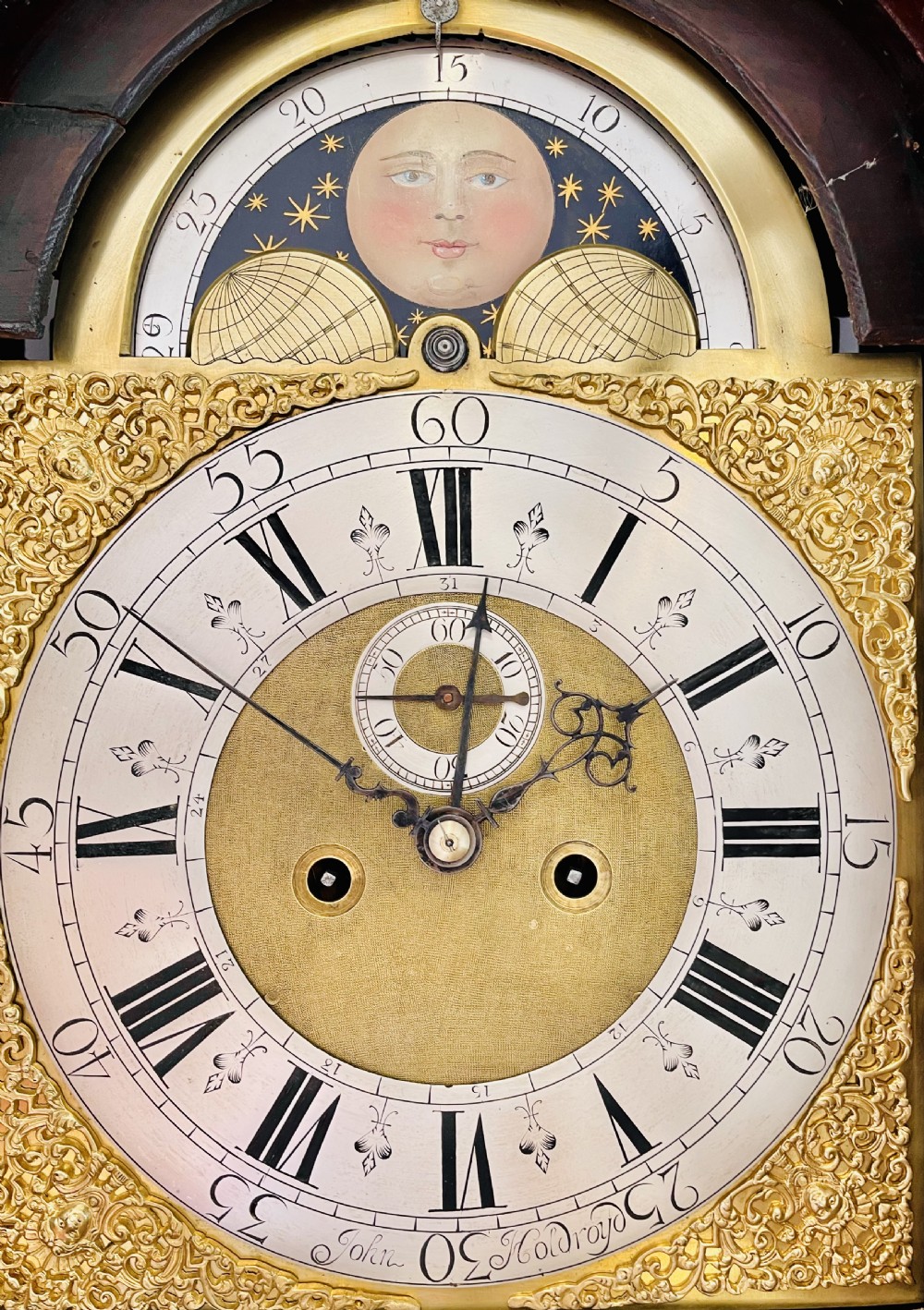 An antique Georgian longcase clock featuring a walnut and oak case, swan-neck pediment, brass finial, and an engraved brass dial with a moonphase display. View IV