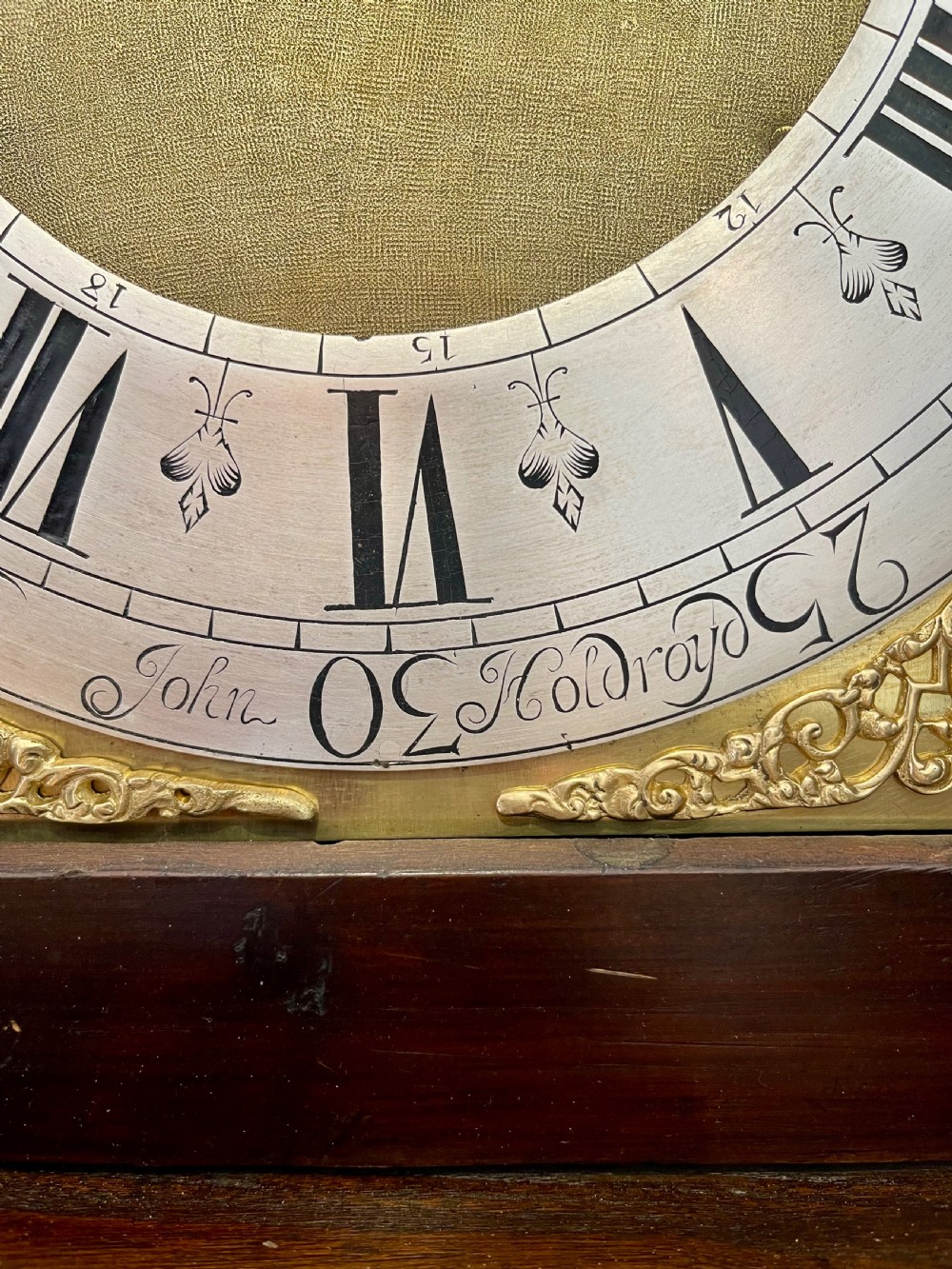 An antique Georgian longcase clock featuring a walnut and oak case, swan-neck pediment, brass finial, and an engraved brass dial with a moonphase display. View XIII