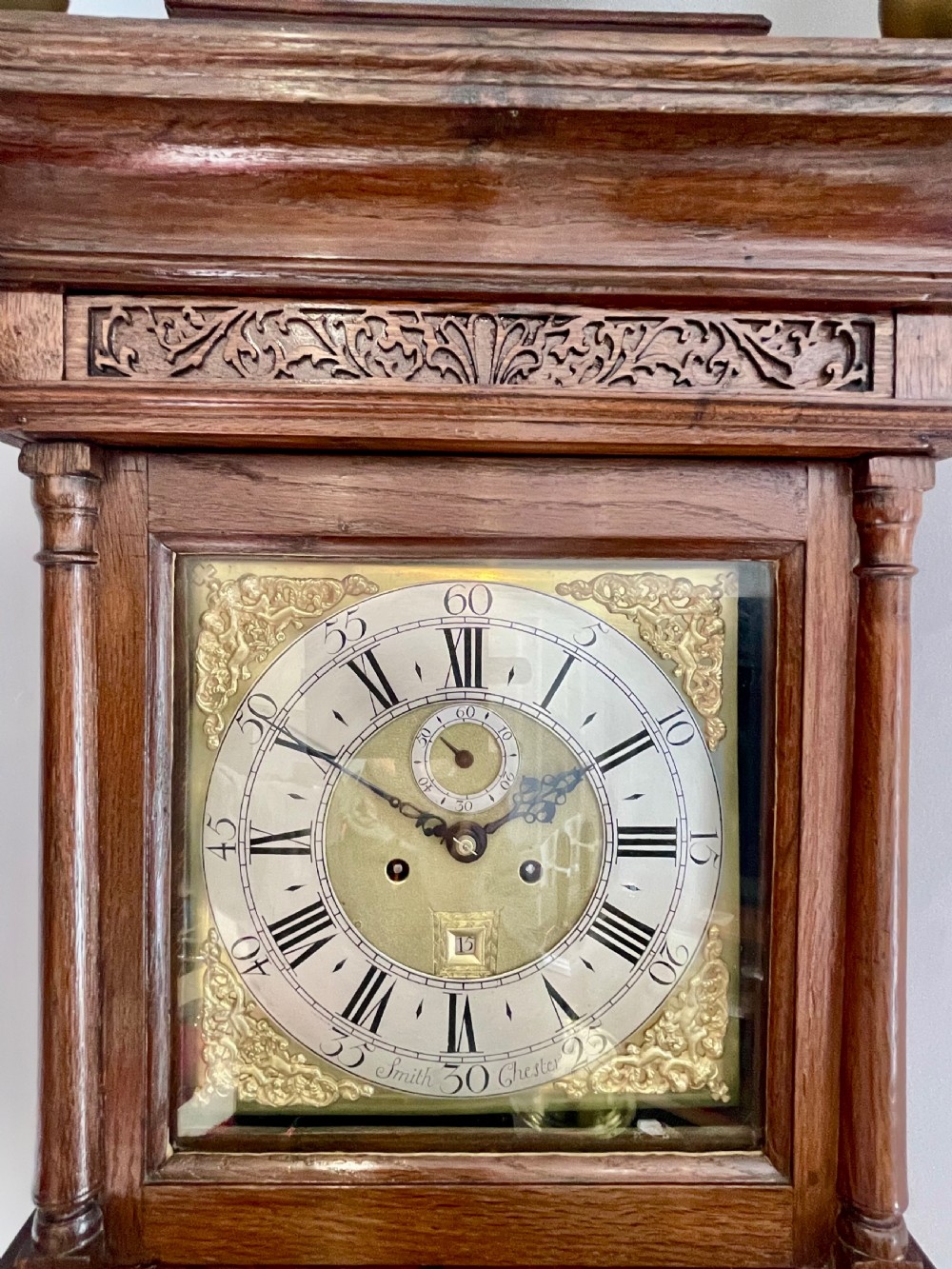 An 18th-century Georgian oak longcase clock featuring a square brass dial with silvered chapter ring, brass spandrels, twin brass finials, and a tall slender timber case. View XIII