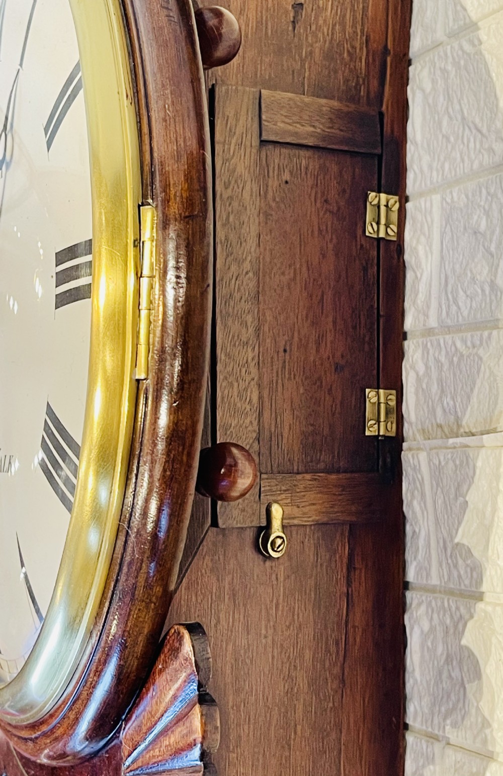 An antique Regency mahogany drop dial wall clock featuring brass line inlay, carved fan side ears, and a cream dial with Roman numerals. View XVI