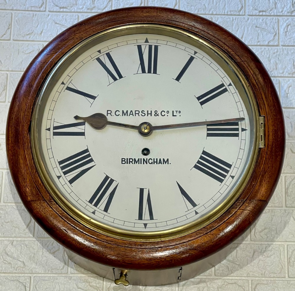 A circular Victorian oak fusee wall clock featuring a white dial with Roman numerals, black hands, and a brass bezel.