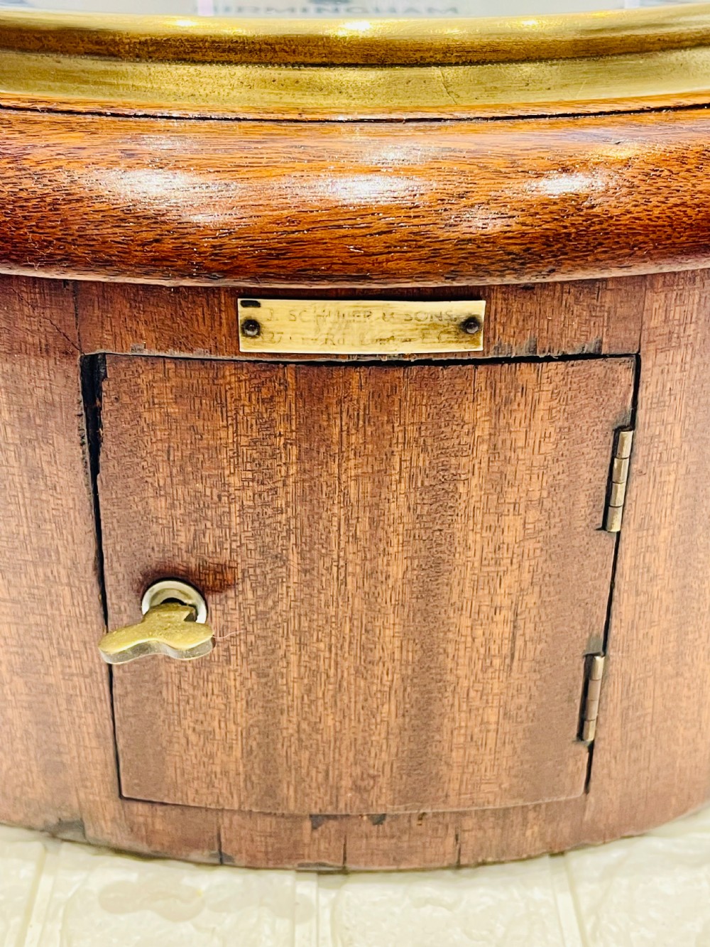 A circular Victorian oak fusee wall clock featuring a white dial with Roman numerals, black hands, and a brass bezel. View XII