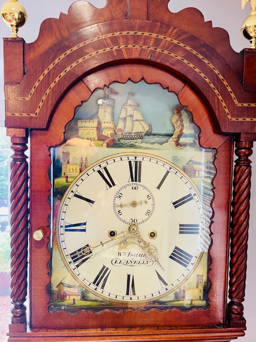 An antique Welsh mahogany longcase clock featuring a painted dial with a rocking ship automaton arch and brass finials. View IV