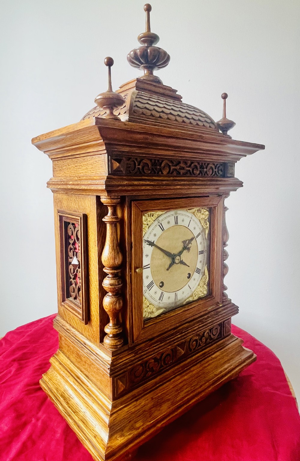 An antique carved oak bracket clock featuring finials, turned columns, and a brass dial with silvered chapter ring. View II