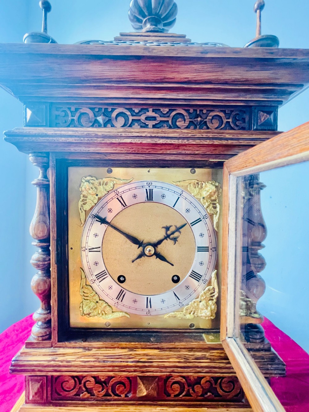 An antique carved oak bracket clock featuring finials, turned columns, and a brass dial with silvered chapter ring. View IV