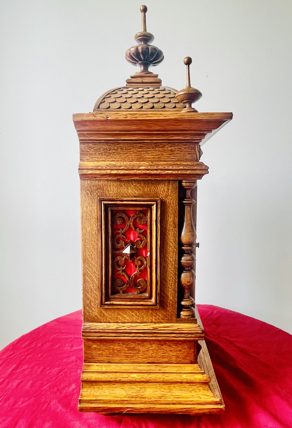An antique carved oak bracket clock featuring finials, turned columns, and a brass dial with silvered chapter ring. View XVII