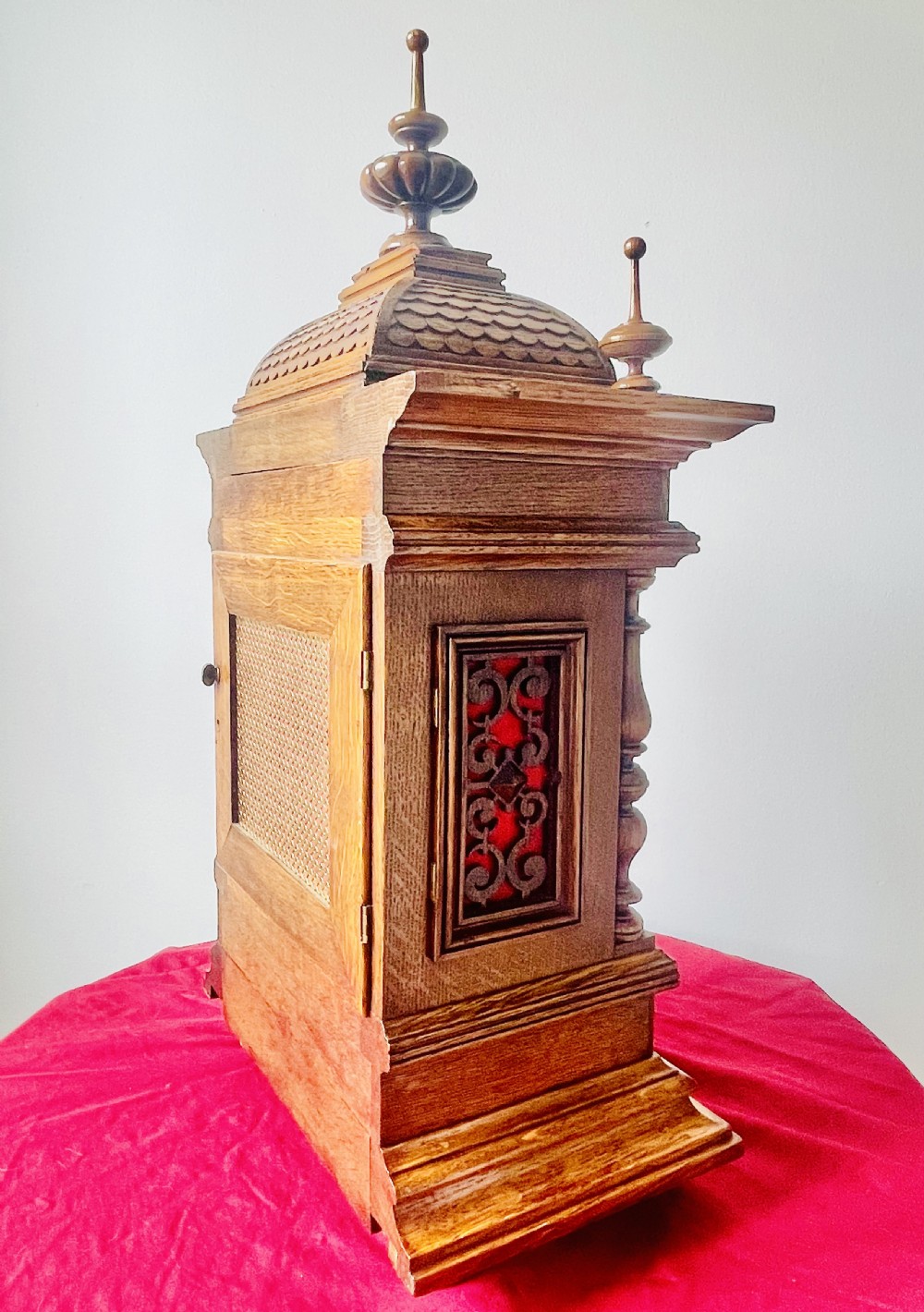 An antique carved oak bracket clock featuring finials, turned columns, and a brass dial with silvered chapter ring. View XVIII