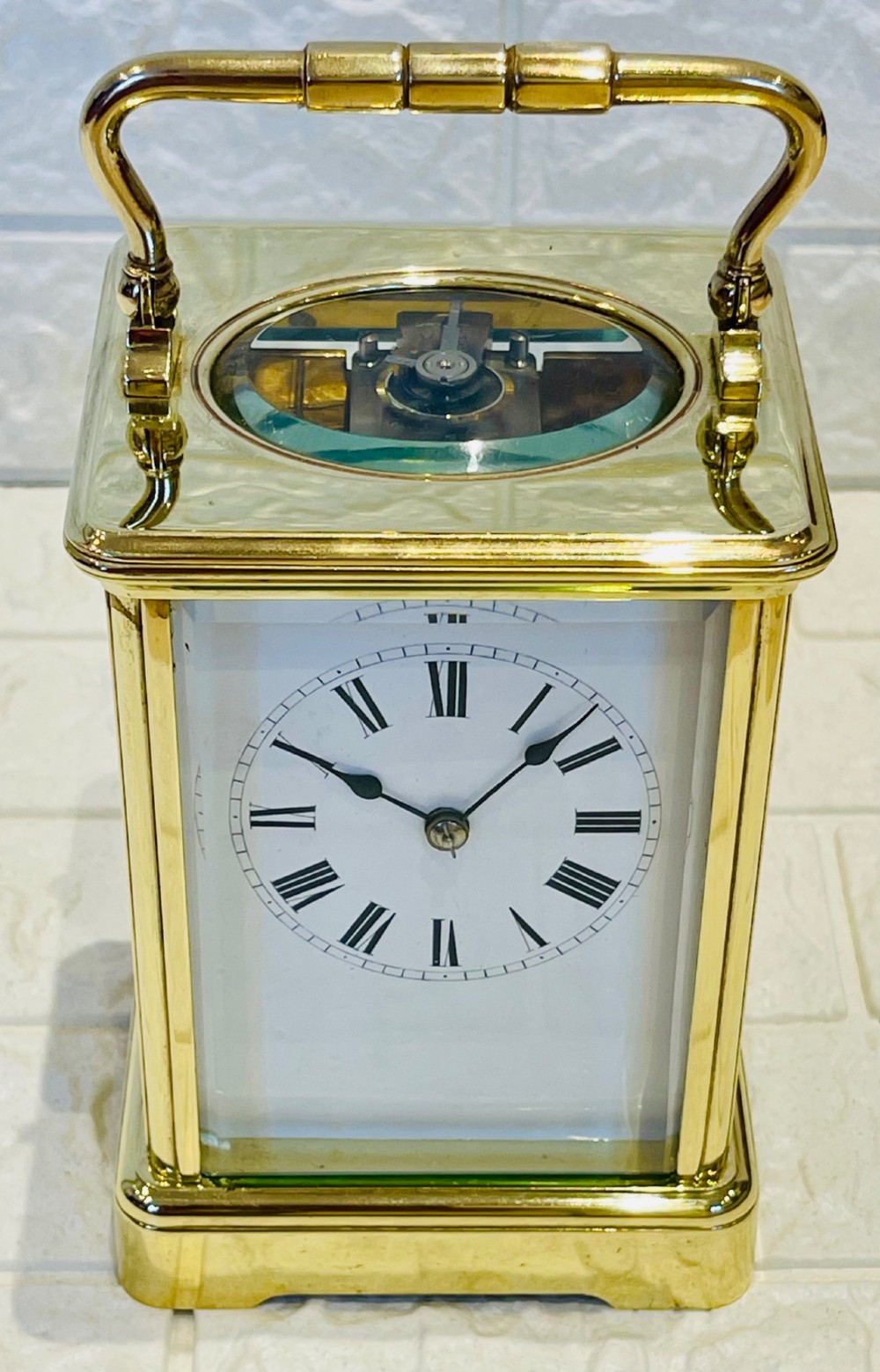 A rectangular French brass carriage clock featuring bevelled glass panels, a top carrying handle, an oval glass escapement window, and a white dial with Roman numerals.
