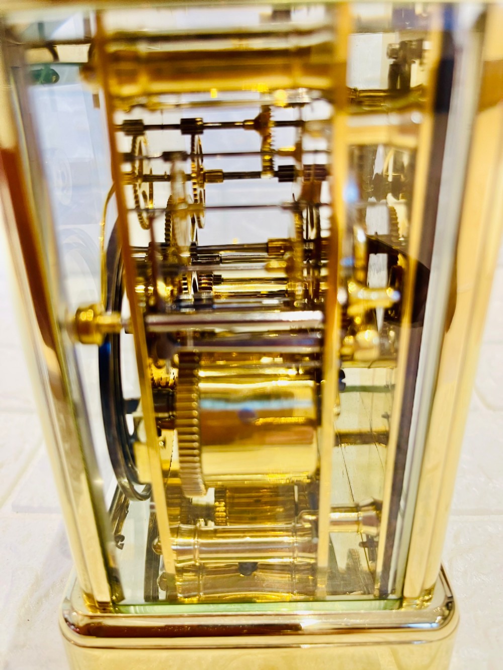 A rectangular French brass carriage clock featuring bevelled glass panels, a top carrying handle, an oval glass escapement window, and a white dial with Roman numerals. View V