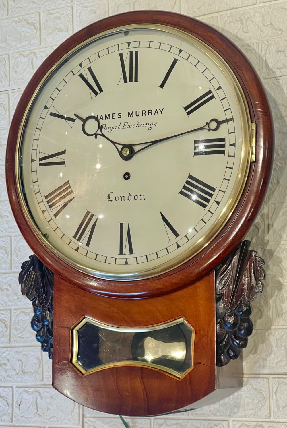 A mahogany drop dial fusee wall clock with a circular white dial signed James Murray London, black Roman numerals, a brass bezel, and carved side details.