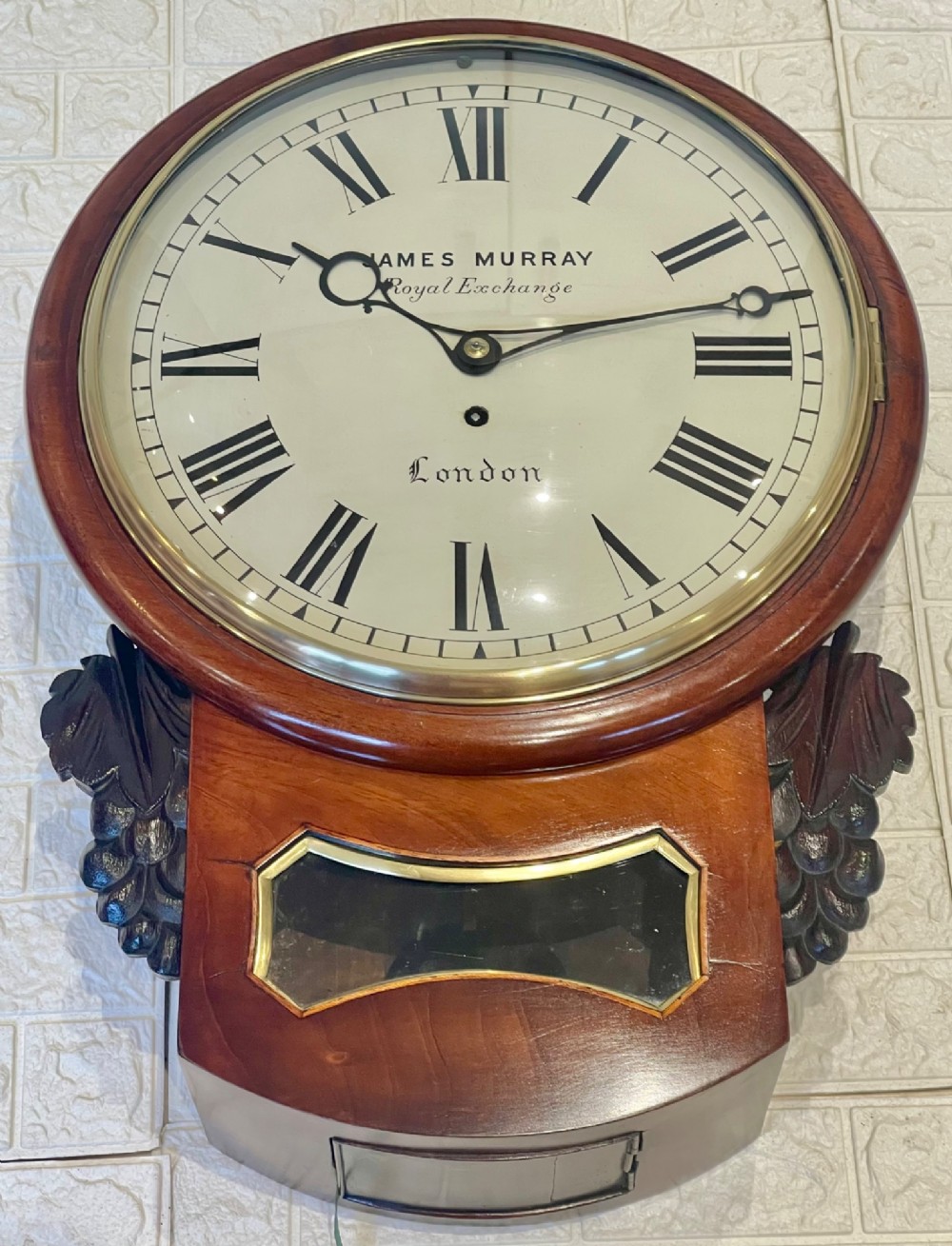 A mahogany drop dial fusee wall clock with a circular white dial signed James Murray London, black Roman numerals, a brass bezel, and carved side details. View II