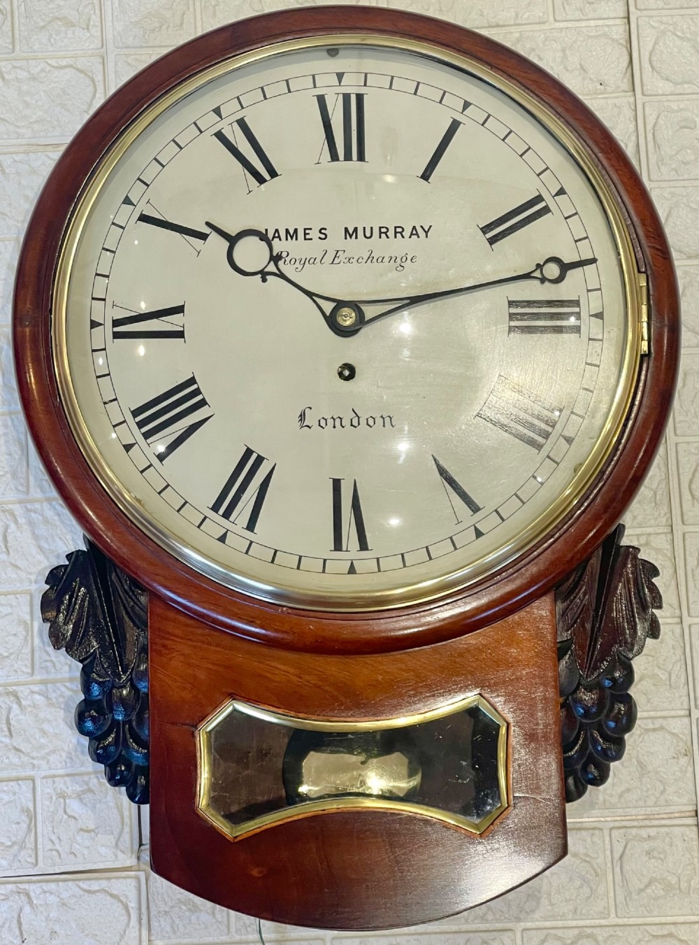 A mahogany drop dial fusee wall clock with a circular white dial signed James Murray London, black Roman numerals, a brass bezel, and carved side details. View III