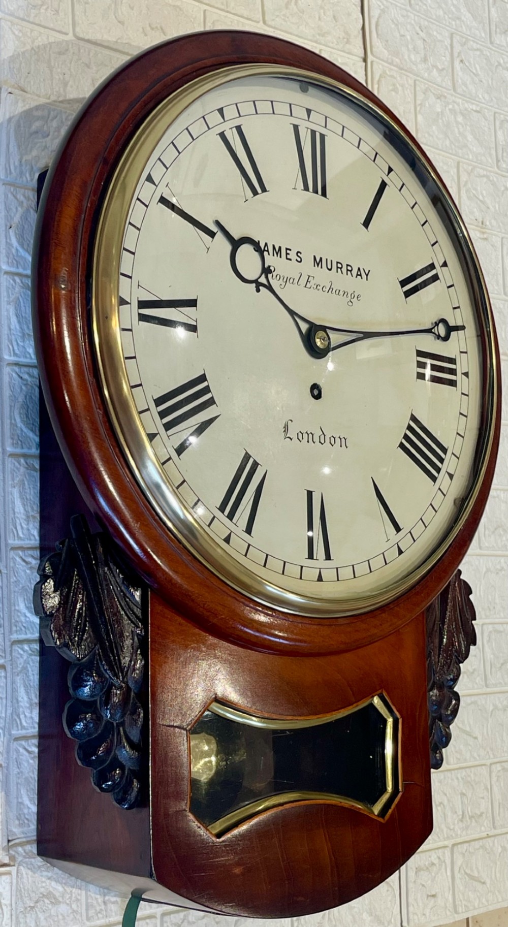 A mahogany drop dial fusee wall clock with a circular white dial signed James Murray London, black Roman numerals, a brass bezel, and carved side details. View VI