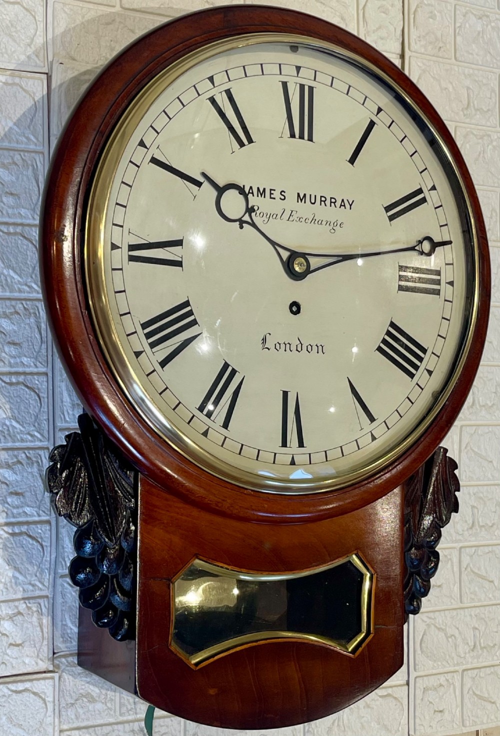 A mahogany drop dial fusee wall clock with a circular white dial signed James Murray London, black Roman numerals, a brass bezel, and carved side details. View VII