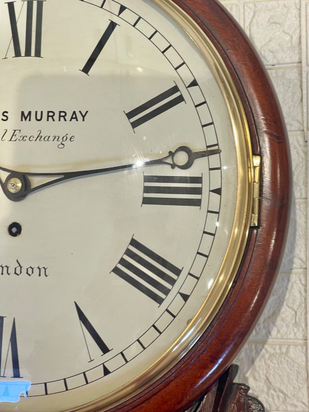 A mahogany drop dial fusee wall clock with a circular white dial signed James Murray London, black Roman numerals, a brass bezel, and carved side details. View X