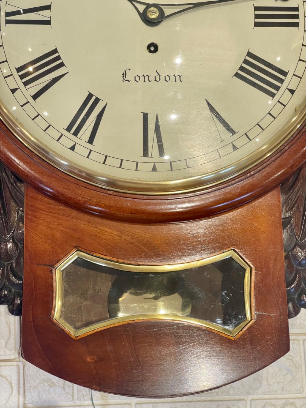 A mahogany drop dial fusee wall clock with a circular white dial signed James Murray London, black Roman numerals, a brass bezel, and carved side details. View XI