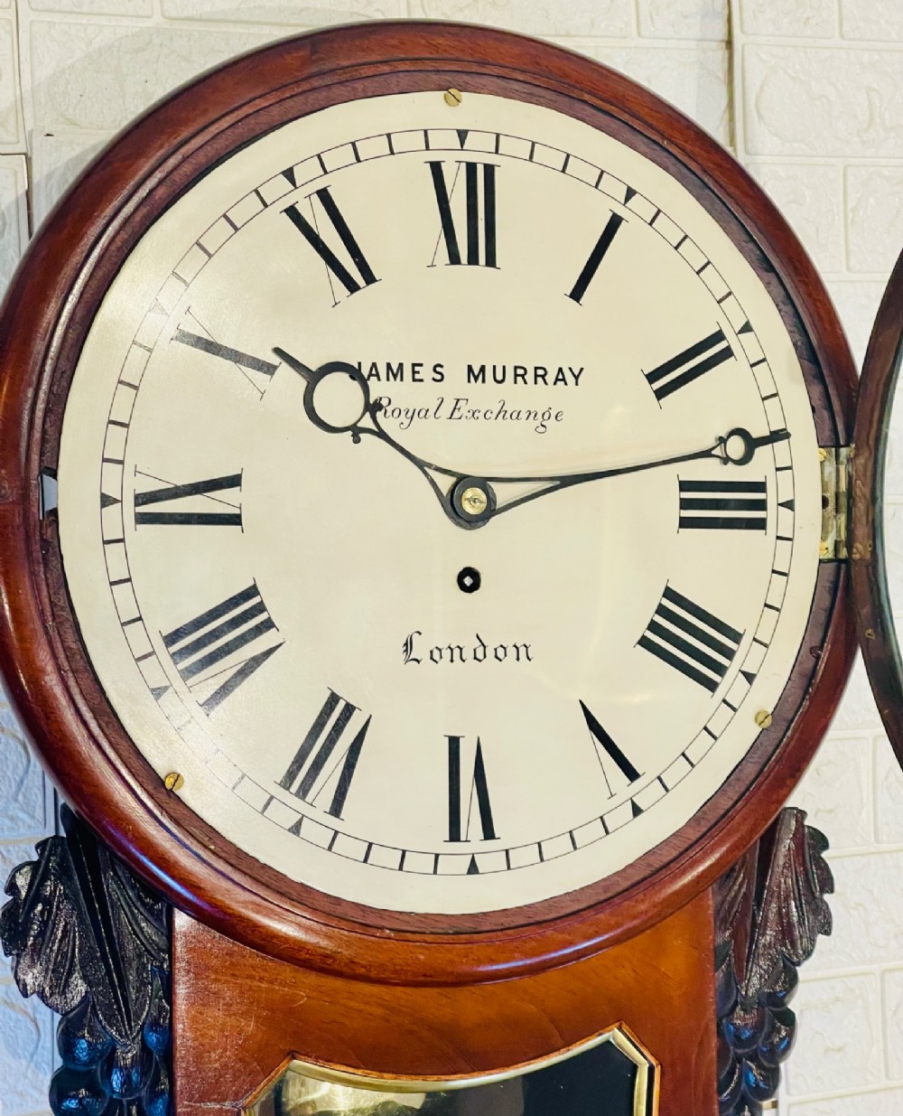 A mahogany drop dial fusee wall clock with a circular white dial signed James Murray London, black Roman numerals, a brass bezel, and carved side details. View XIII