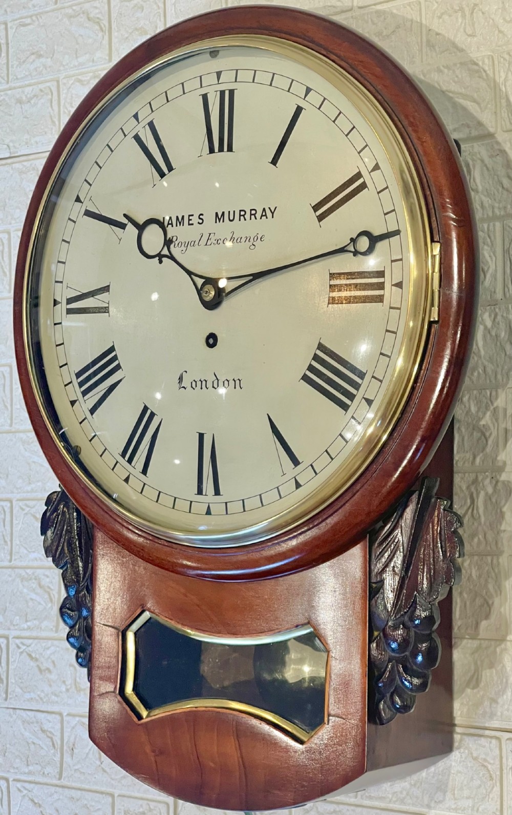 A mahogany drop dial fusee wall clock with a circular white dial signed James Murray London, black Roman numerals, a brass bezel, and carved side details. View XIV
