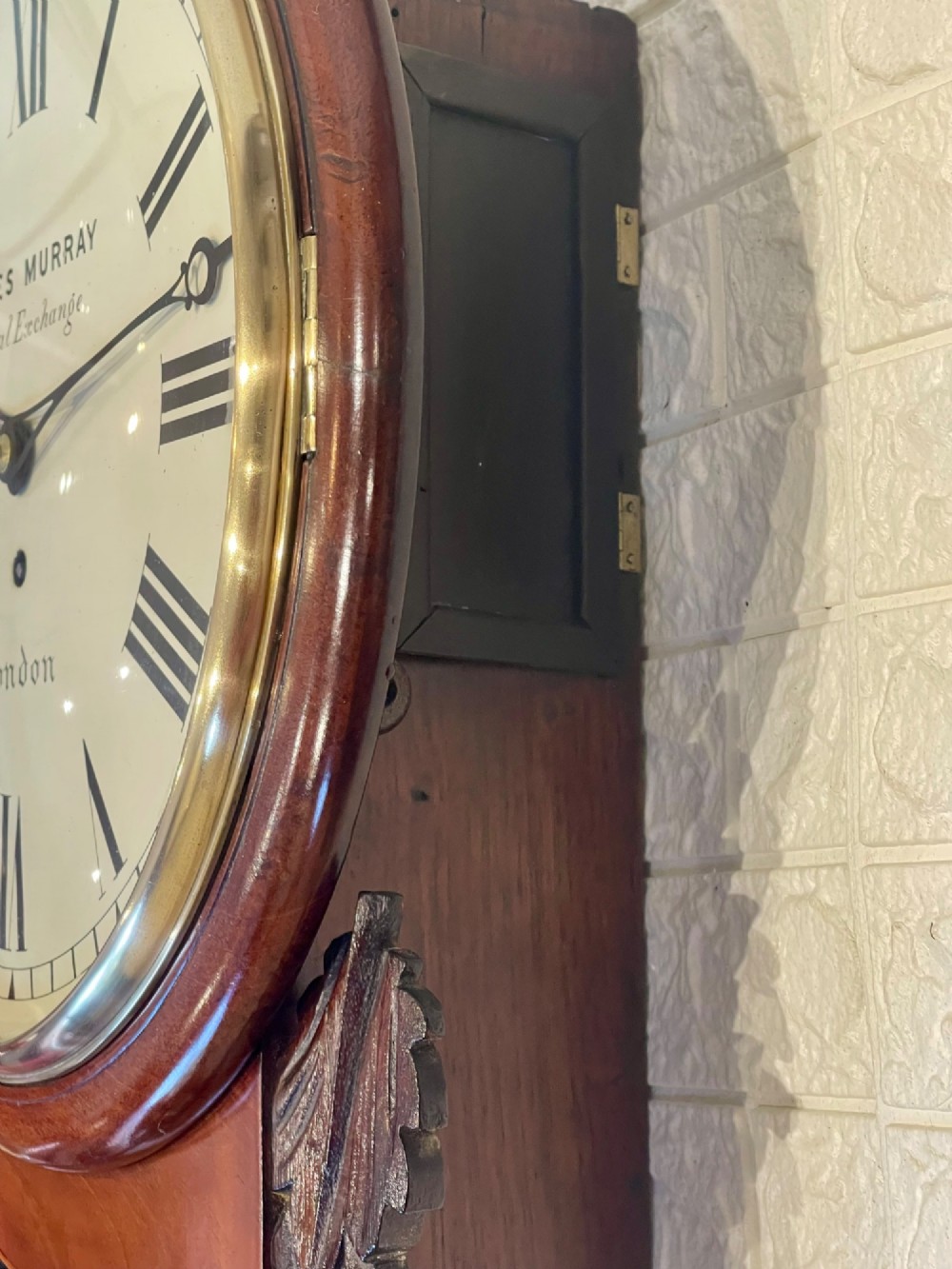 A mahogany drop dial fusee wall clock with a circular white dial signed James Murray London, black Roman numerals, a brass bezel, and carved side details. View XV