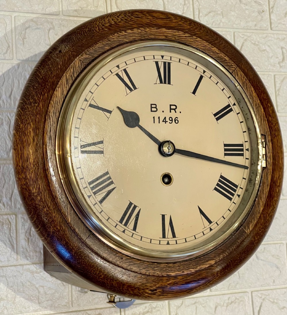 A circular oak wall clock featuring a brass bezel, Roman numerals, and British Rail markings printed on the dial. View II