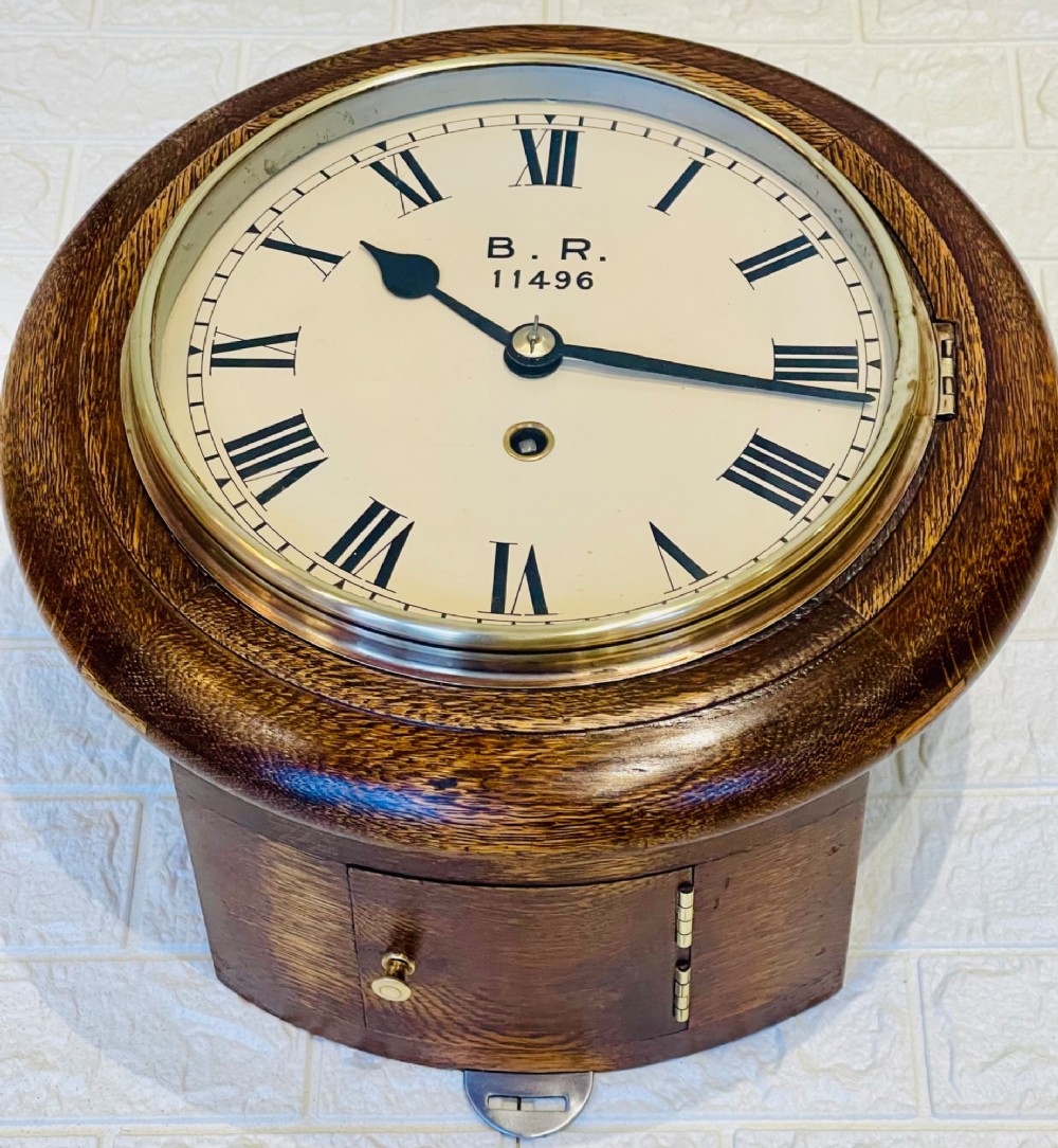 A circular oak wall clock featuring a brass bezel, Roman numerals, and British Rail markings printed on the dial. View III