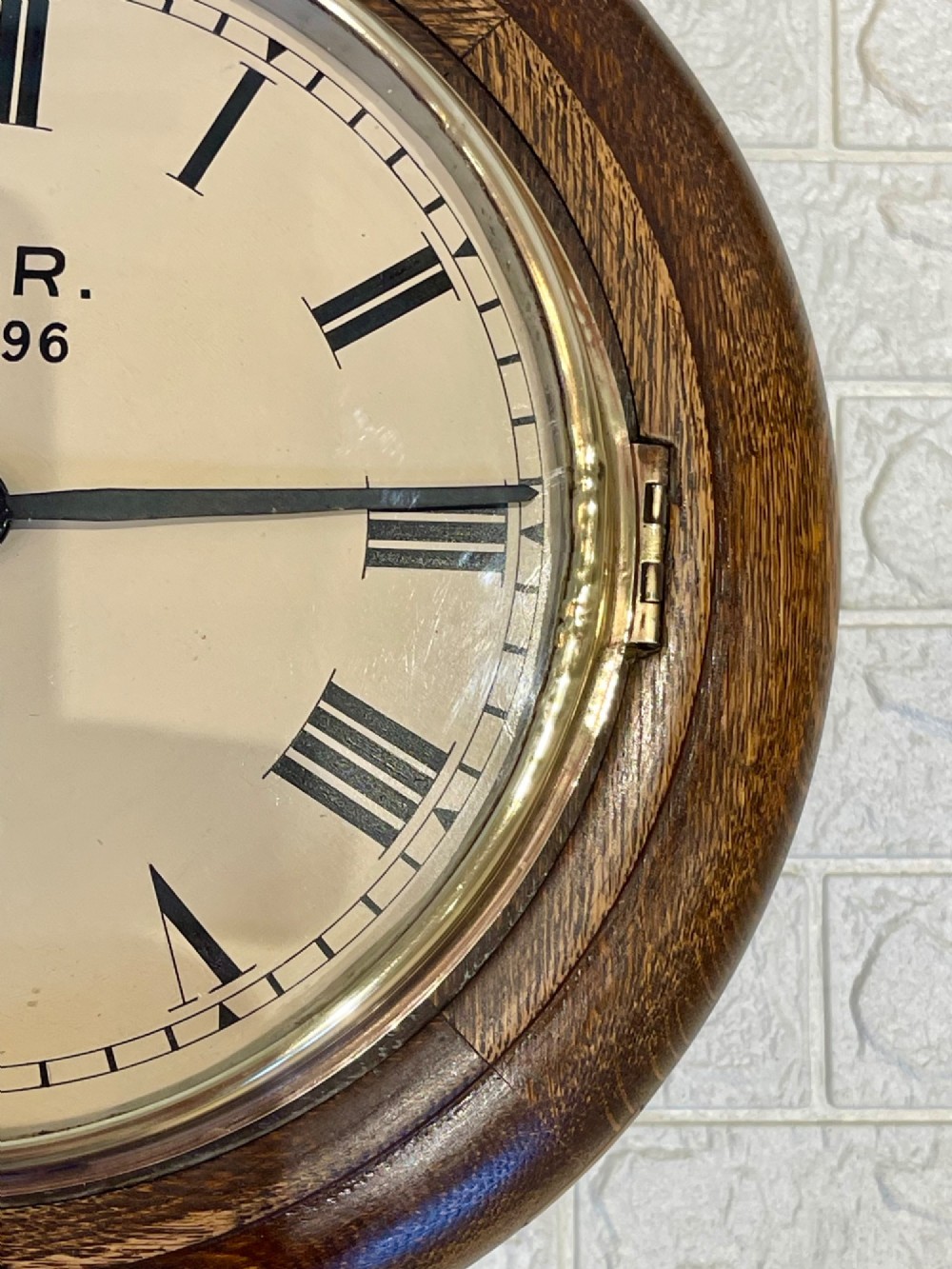 A circular oak wall clock featuring a brass bezel, Roman numerals, and British Rail markings printed on the dial. View IV
