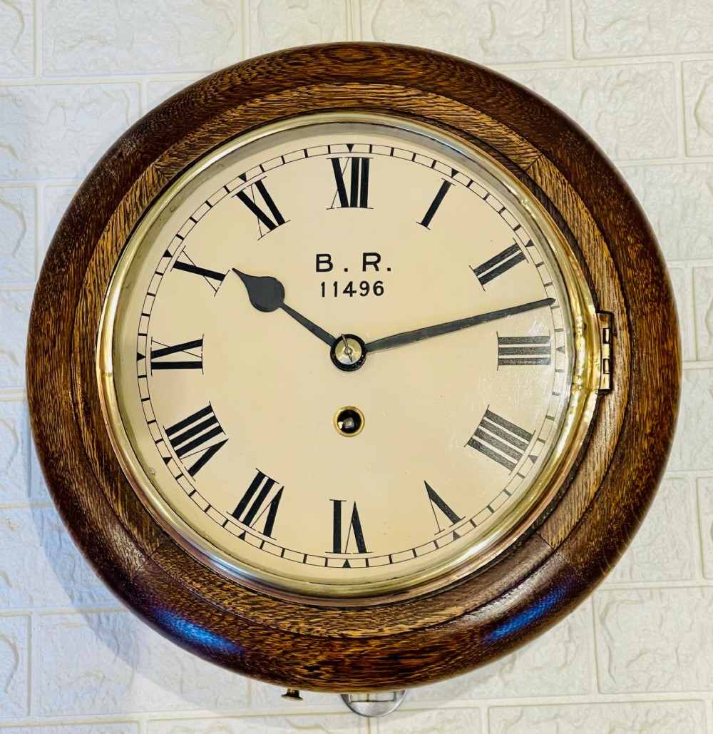 A circular oak wall clock featuring a brass bezel, Roman numerals, and British Rail markings printed on the dial. View VI