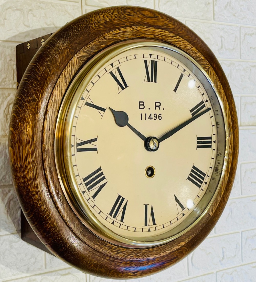 A circular oak wall clock featuring a brass bezel, Roman numerals, and British Rail markings printed on the dial. View IX