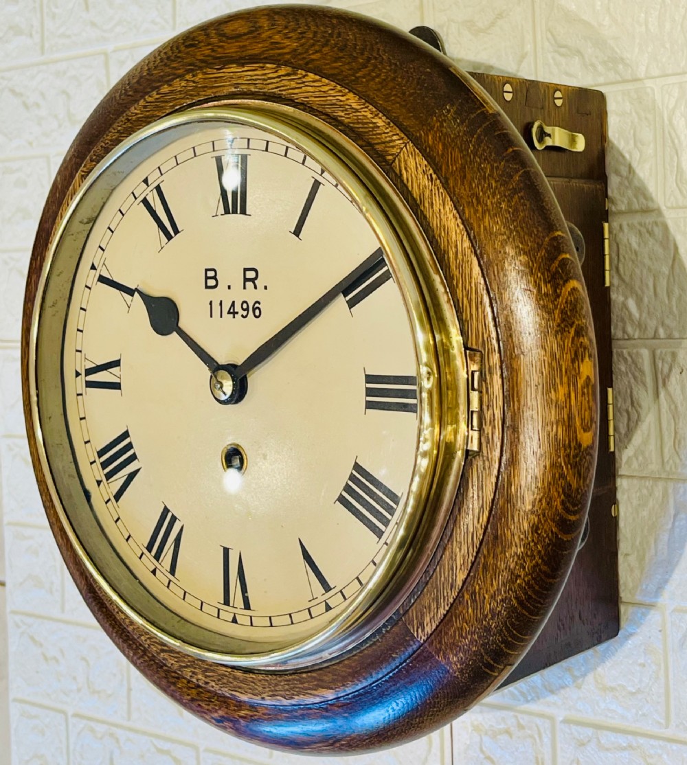 A circular oak wall clock featuring a brass bezel, Roman numerals, and British Rail markings printed on the dial. View XII