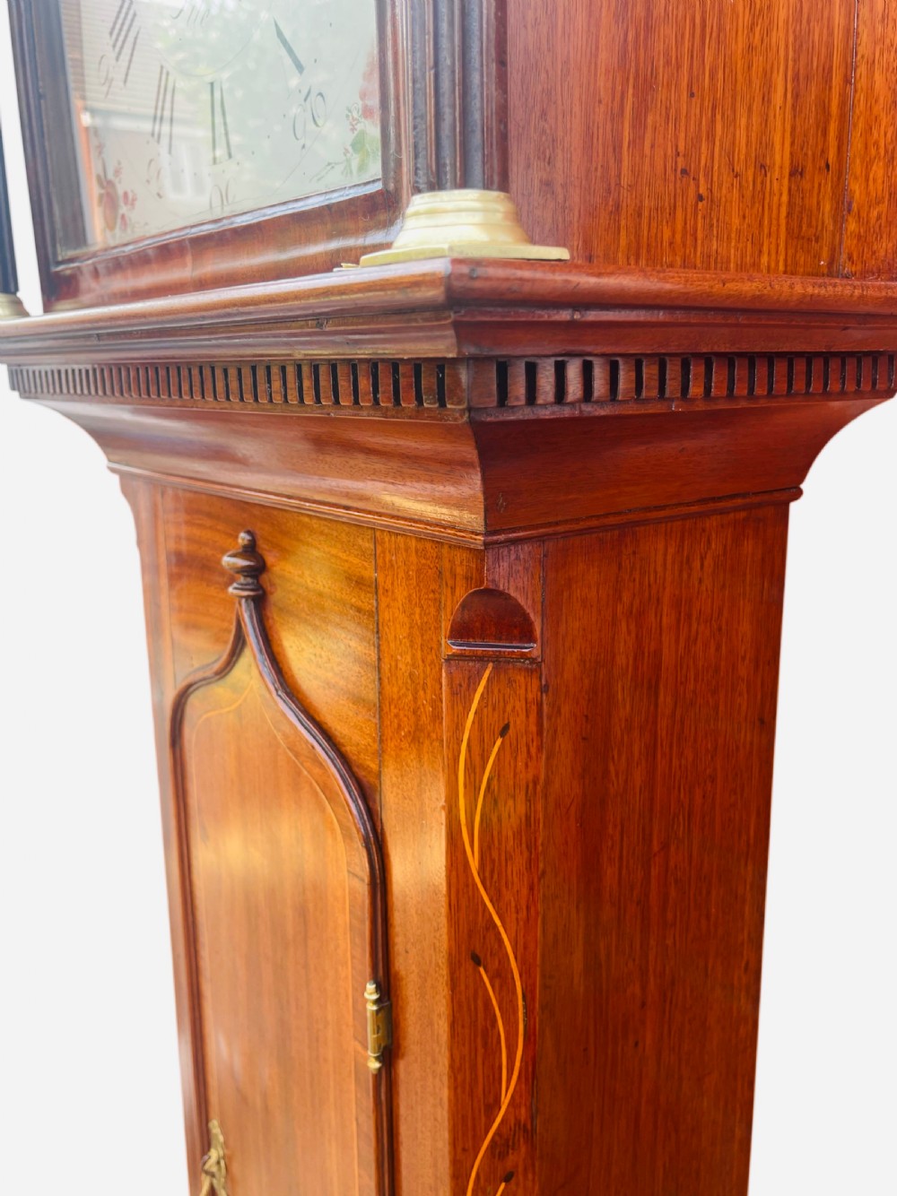 A Georgian oak longcase clock featuring a fretwork pediment, brass finial, hand-painted dial with Roman numerals, and an arched waist door. View VI