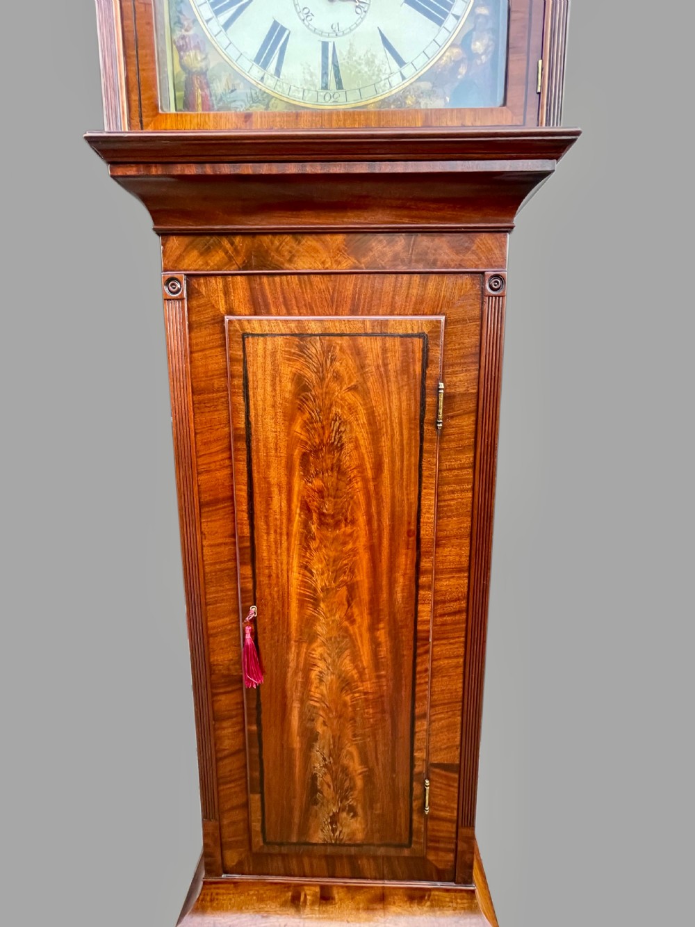 A Georgian flame mahogany longcase clock featuring a swan-neck pediment and a hand-painted arch dial. View XII