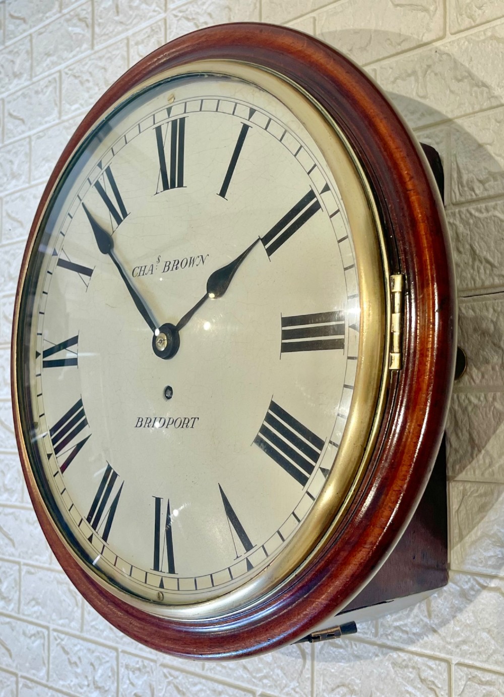 A circular Georgian fusee wall clock with a dark mahogany frame, a cream painted dial with Roman numerals, and a polished brass bezel. View V