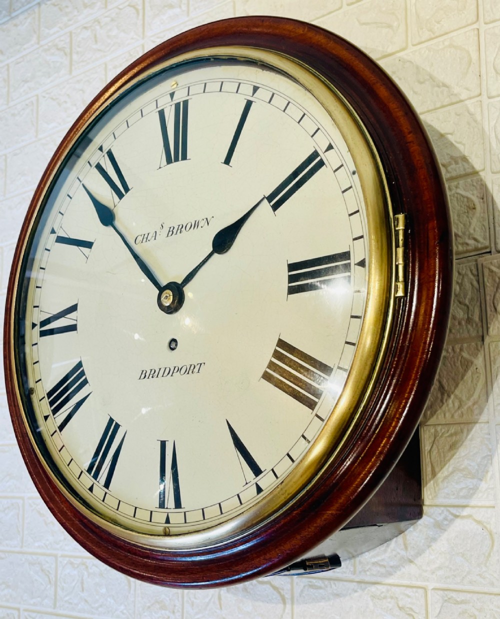 A circular Georgian fusee wall clock with a dark mahogany frame, a cream painted dial with Roman numerals, and a polished brass bezel. View VI
